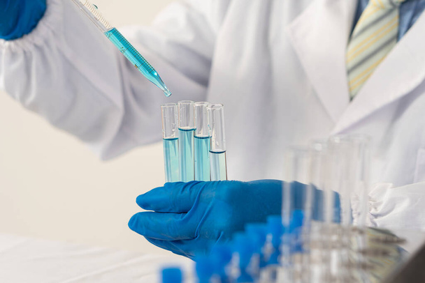 modern laboratórium A tudósok kísérletet végeznek azáltal, hogy egy vegyületet szintetizálnak egy palackban a kezükben. A tudósok COVID-19 elleni vakcinákat tesztelnek.. - Fotó, kép