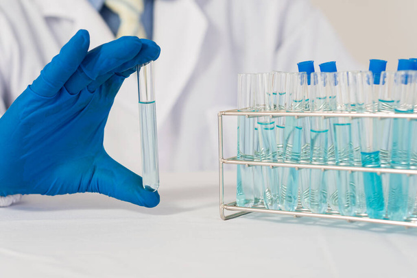 современные лабораторные ученые проводят эксперимент путем синтеза соединения в бутылке в руке. Ученые тестируют вакцины против COVID-19. - Фото, изображение