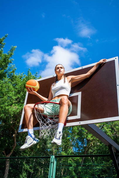 Young beautiful brunette girl posing on the basketball court - 写真・画像