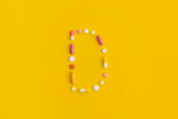 Vitamin D made from pills on yellow background. Top view with copy space. Flat lay. - Fotoğraf, Görsel