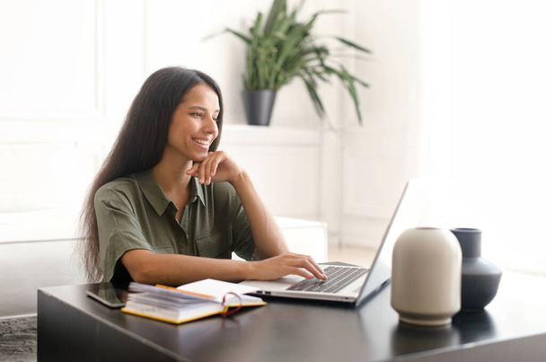 Cheerful indian young woman using laptop computer for remote work - 写真・画像