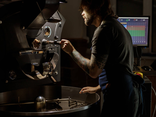 Fabrikada kahve kızartma makinesi işleten erkek işçi. - Fotoğraf, Görsel