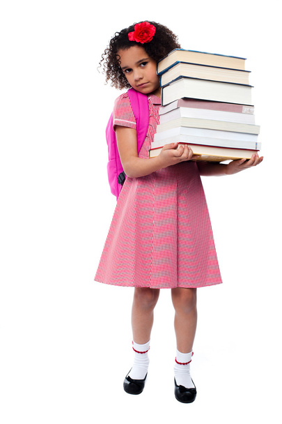 Schoolgirl carrying stack of books - 写真・画像