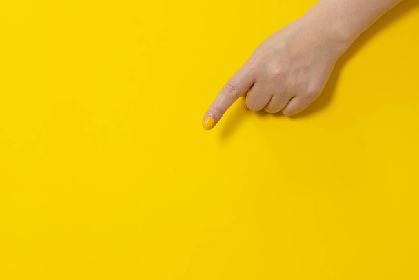 Δάχτυλο χέρι δείχνει κάτι σε κίτρινο φόντο, closeup. Με χειρονομίες. Μπάνερ. - Φωτογραφία, εικόνα