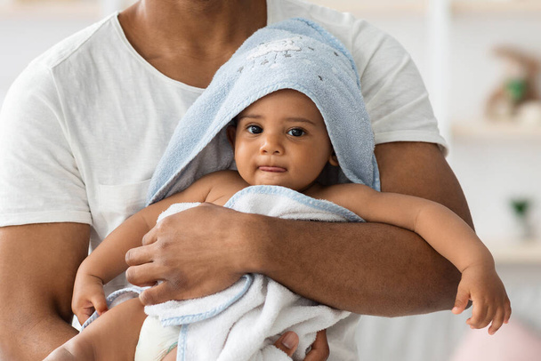Adorabile bambino neonato nero in asciugamano rilassante nelle braccia dei padri dopo il bagno - Foto, immagini