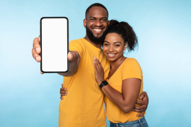 Nieuwe geweldige mobiele app. Afro-Amerikaanse paar presenteren smartphone met mockup, bevordering van toepassing of website - Foto, afbeelding