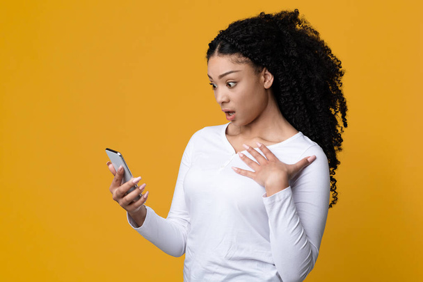 Šokující obsah. Omámený černošky americká žena při pohledu na Smartphone obrazovce - Fotografie, Obrázek