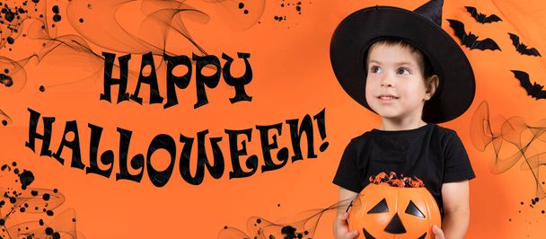 Banner Boldog Halloweent. Egy óvodás fiú boszorkányjelmezben tart egy sütőtököt cukorkával narancssárga alapon.. - Fotó, kép