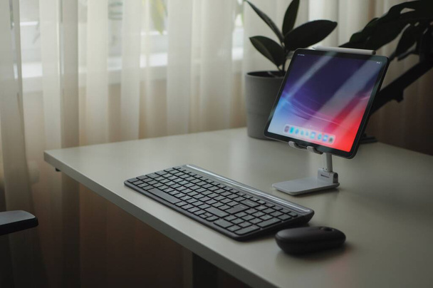 Elegante local de trabalho doméstico com dispositivo tablet em stand com mouse e teclado - Foto, Imagem