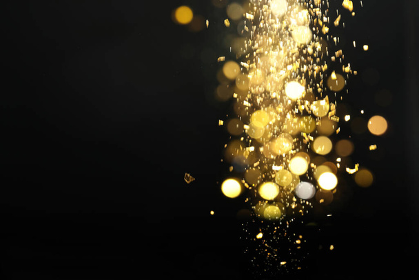 Blurred view of golden lights on black background. Bokeh effect - Zdjęcie, obraz