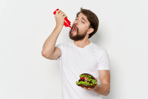 Homem com hambúrguer a comer molho, comida de plástico. Foto de alta qualidade - Foto, Imagem