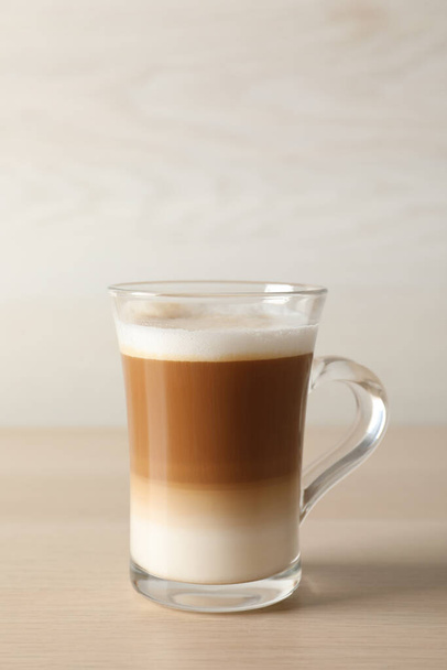 Horká káva s mlékem ve skleněném šálku na dřevěném stole - Fotografie, Obrázek