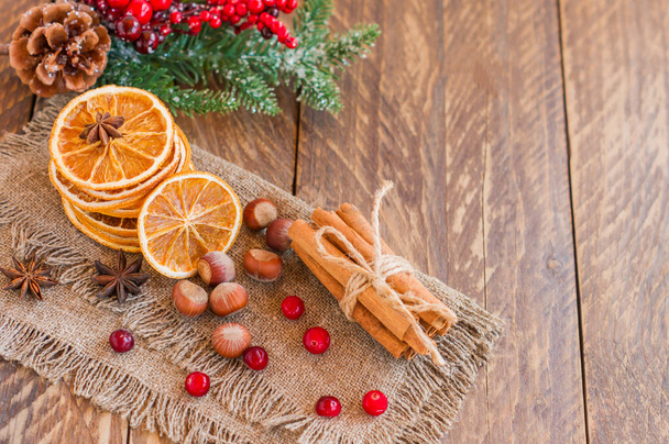 Christmas composition with spruce tree branches, cinnamon sticks, dried slices of oranges, nuts and anise on wooden background. Rustic style - Φωτογραφία, εικόνα