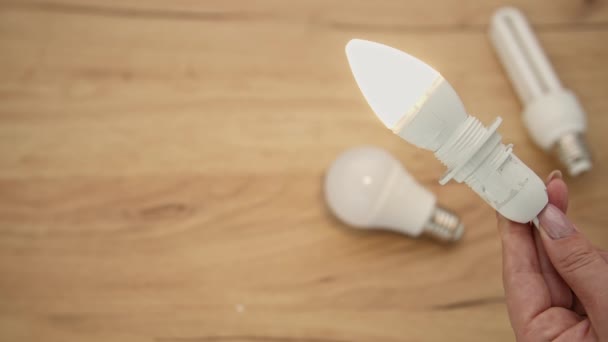 sähkö, moderni sähkölamppu kädessä palaa taustalla muiden lamppujen, lähikuva - Materiaali, video