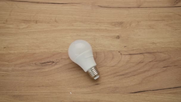 elektřina, bílá lampa pro osvětlení místnosti leží na dřevěném pozadí - Záběry, video