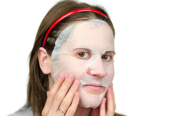 Young woman in a paper moisturizing mask. Facial skin care - Photo, Image