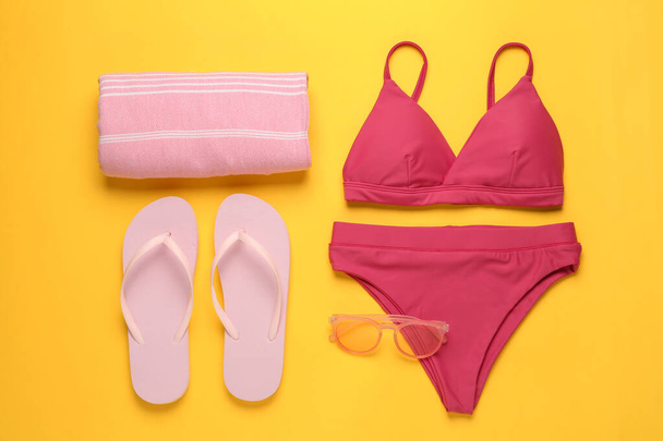 Stylish bikini and beach accessories on yellow background, flat lay - Fotoğraf, Görsel