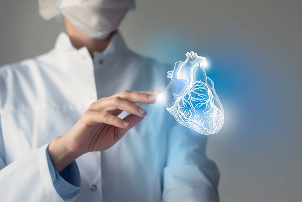 Female doctor touchstone virtual Heart in hand. Blurred photo, handrawn human organ, highlighted blue as symbol of recovery. Healthcare hospital service concept stock photo - Фото, зображення