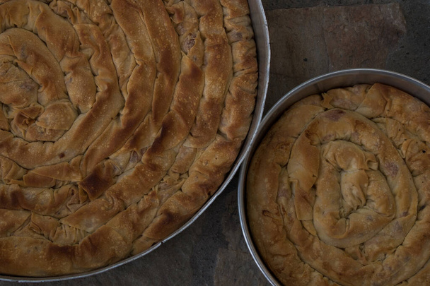 gebakken zelfgebakken traditionele Griekse kaas twist taart in twee ijzeren oven pan met filo, spinazie, mizithra en feta kaas. - Foto, afbeelding