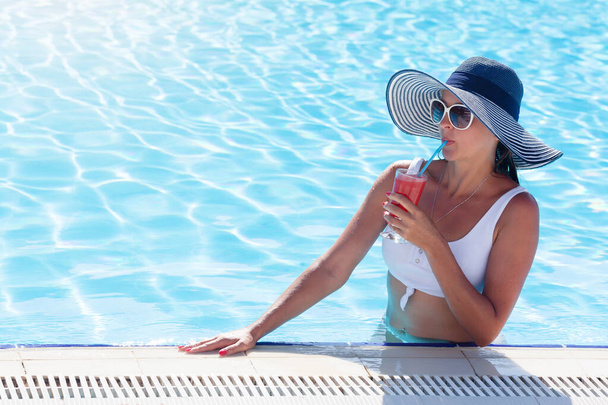 Vrouw ontspannen bij het zwembad met tropische cocktail. met kopieerruimte - Foto, afbeelding