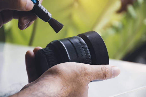 pulitura a mano umana polvere sulla lente della fotocamera con pennello pulitore - Foto, immagini