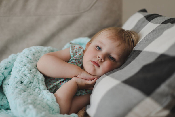 Cute little two years old girl lying under plaid at home - Фото, зображення