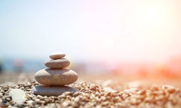 Дзен-камни это фон. Пирамида из камешков на фоне неба, моря и пляжа. Медитация, йога, успокаивание ума и релаксация. - Фото, изображение
