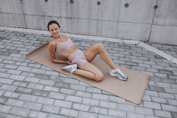 Une jeune femme caucasienne sportive mince s'entraîne, fait du fitness, yoga dans la rue de la ville. - Photo, image