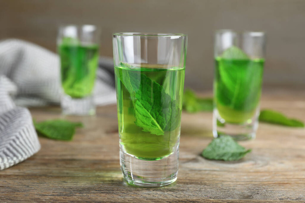 Delicious mint liqueur with green leaves on wooden table - Foto, immagini