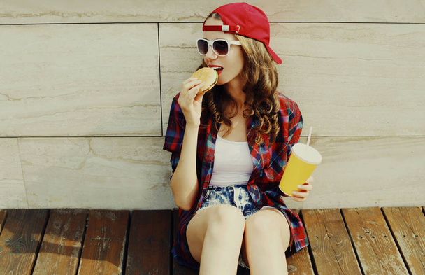 Portrait of happy smiling young woman with burger and cup of juice fast food in the city - Fotoğraf, Görsel