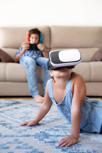 Blanke kleine meid die plezier heeft thuis met een virtual reality bril. Ruimte voor tekst. - Foto, afbeelding
