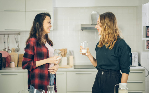 дві жінки п'ють молоко на кухні
 - Фото, зображення