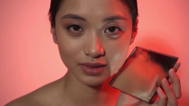 jonge vrouw met perfecte huid in de buurt spiegel op roze - Video