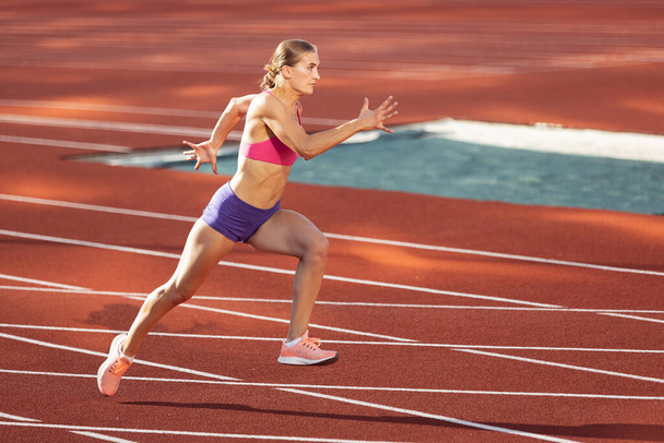 Track-and-field athletics. Young Caucasian woman, professional athlete, runner training at public stadium, sport court, outdoors. Concept of sport, achievment, motion. - Φωτογραφία, εικόνα