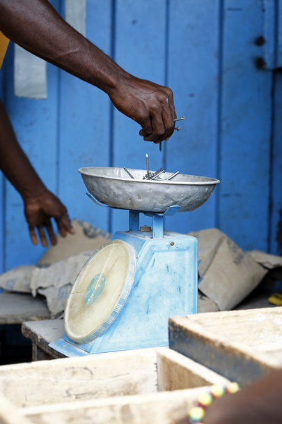 carpinteiro africano pesa pregos em uma balança
  - Foto, Imagem