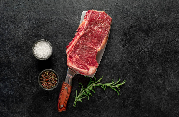 сирий яловичий стейк зі спеціями та травами на чорному фоні
 - Фото, зображення