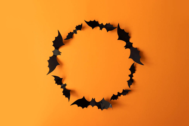 Halloween-Urlaubskonzept mit schwarzem Fledermausrahmen auf orangefarbenem Hintergrund, Draufsicht. Plakat, Gutschein, Angebot, Gutschein, Urlaubsverkauf. - Foto, Bild