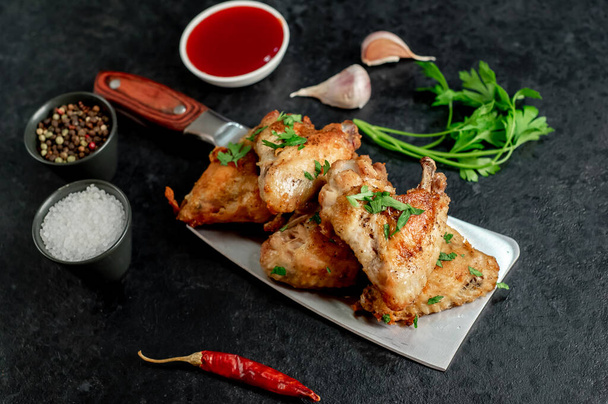 fried chicken wings with spices and herbs on black background - 写真・画像