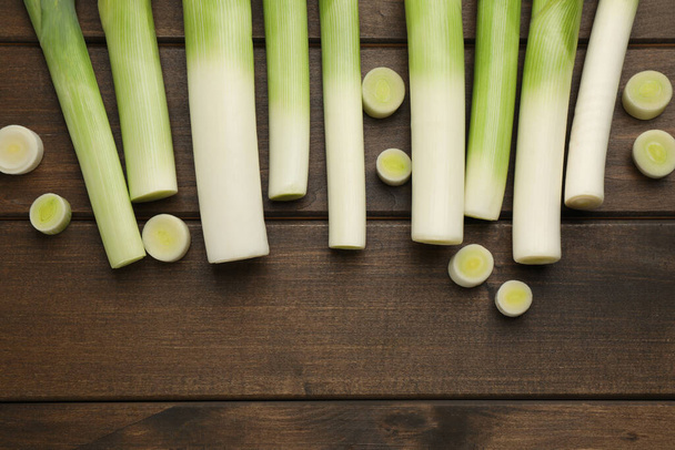 Whole and cut fresh leeks on wooden table, flat lay. Space for text - Фото, изображение