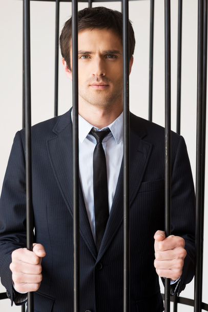 Man in formalwear standing behind a prison cell - Photo, image