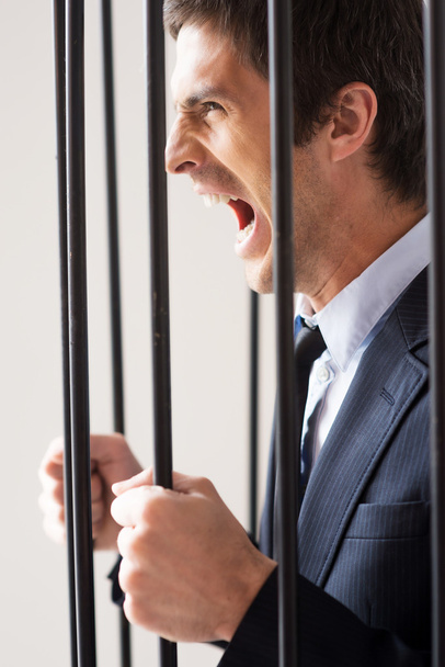 Man in formalwear standing behind a prison cell - Zdjęcie, obraz