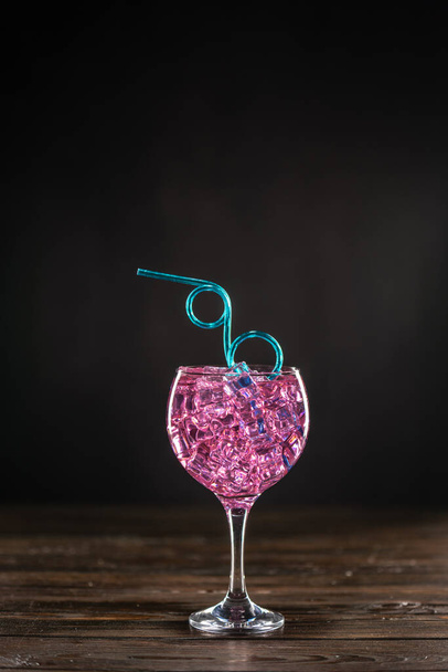 Sklenice s růžovým koktejlem plným ledu na tmavém pozadí - Fotografie, Obrázek