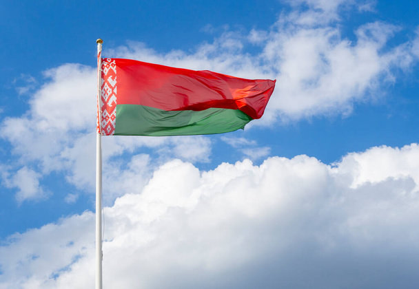 Flag of Belarus on flagpole waving against blue sky - Fotó, kép