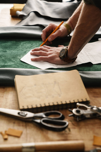 Artesano blanco trabajando con cuero en mesa de madera en taller - Foto, Imagen