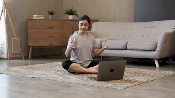 подходит спортивные здоровые спокойные женщины сидят на коврик в позе лотоса смотреть онлайн йога класс медитировать делать дыхательные упражнения на ноутбуке  - Кадры, видео
