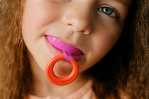 mouth guard - myofunctional trainer to eliminates mouth breathing habit, helps equalize the growing teeth and correct bite. mouthguard in the mouth of a girl close-up. A device for leveling teeth - Photo, Image