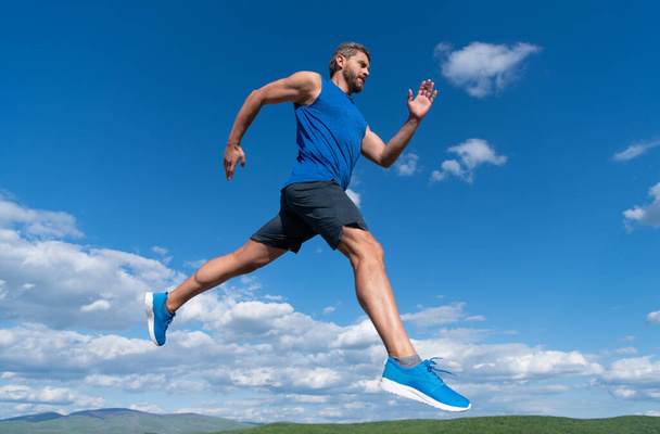 sportoló sprinter izmos test futó sportruházat szabadtéri égbolt háttér, állóképesség. - Fotó, kép