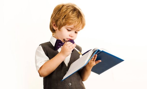 Un niño escribiendo en un cuaderno. Colegial con uniforme escolar. Regreso a la escuela. - Foto, Imagen