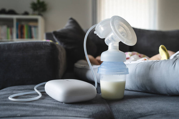 Elektrische Borstpomp Borstvoeding Machine en fles met melk op bed - Foto, afbeelding