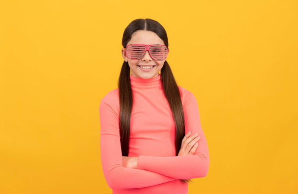 niño sonriente en gafas de fiesta glamour sobre fondo amarillo, look elegante - Foto, Imagen